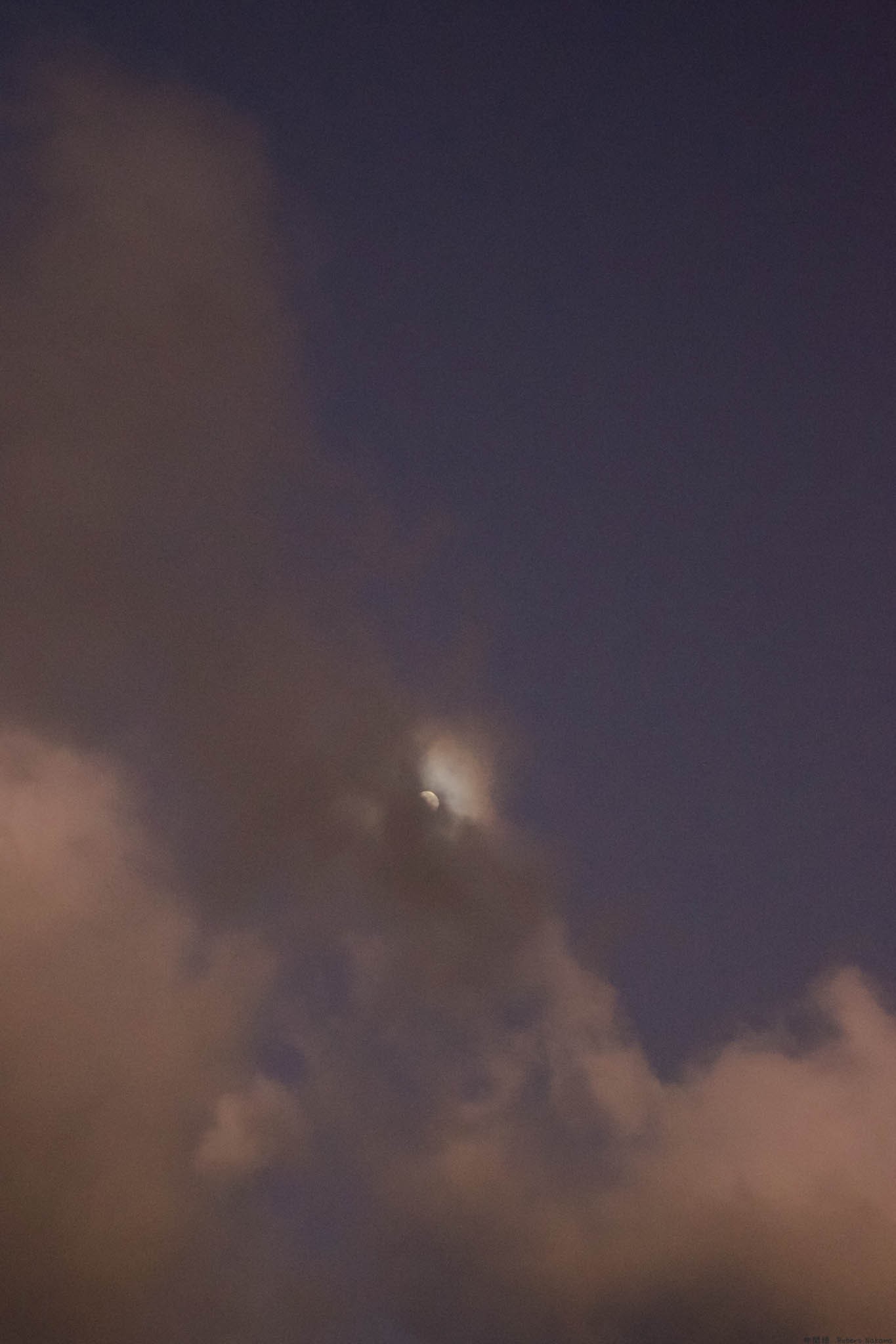 Moon hiding in the clouds at dusk